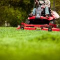 Gardener in the park on a lawn cutting tractor machine